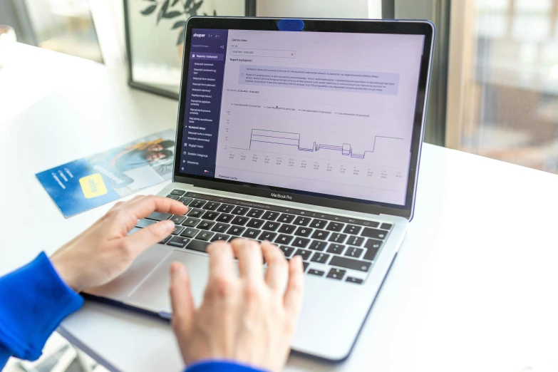 a woman is typing on a laptop with a credit card on the keyboard