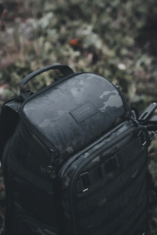 a black camo print back pack with one strap