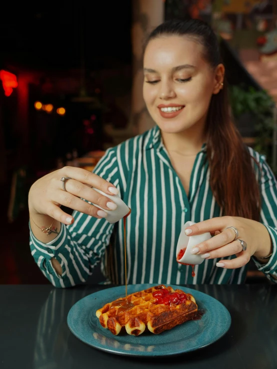 a woman sitting at a table making a sandwich