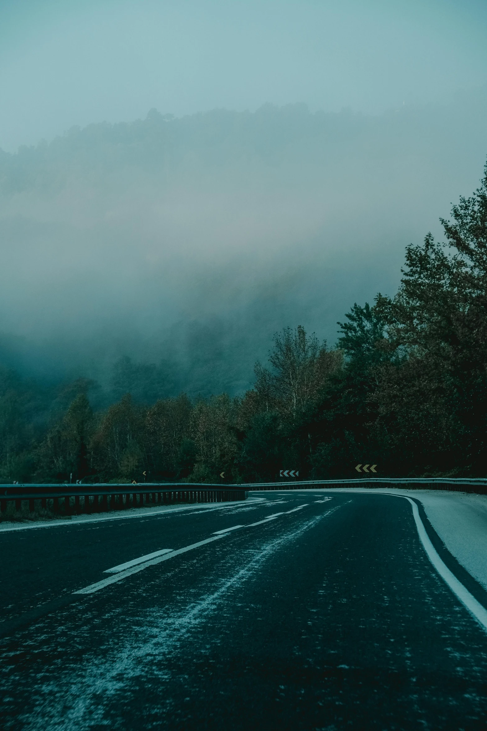 the view from a road that is surrounded by trees and mountains