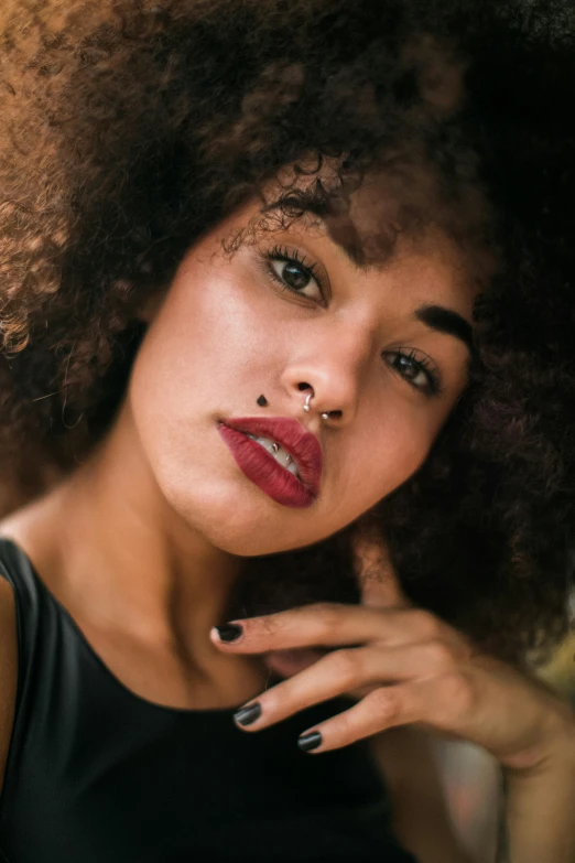 a woman with dark red lipstick and piercings posing for the camera