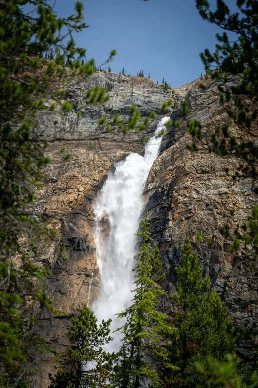 a view of a waterfall in the mountains from a cliff