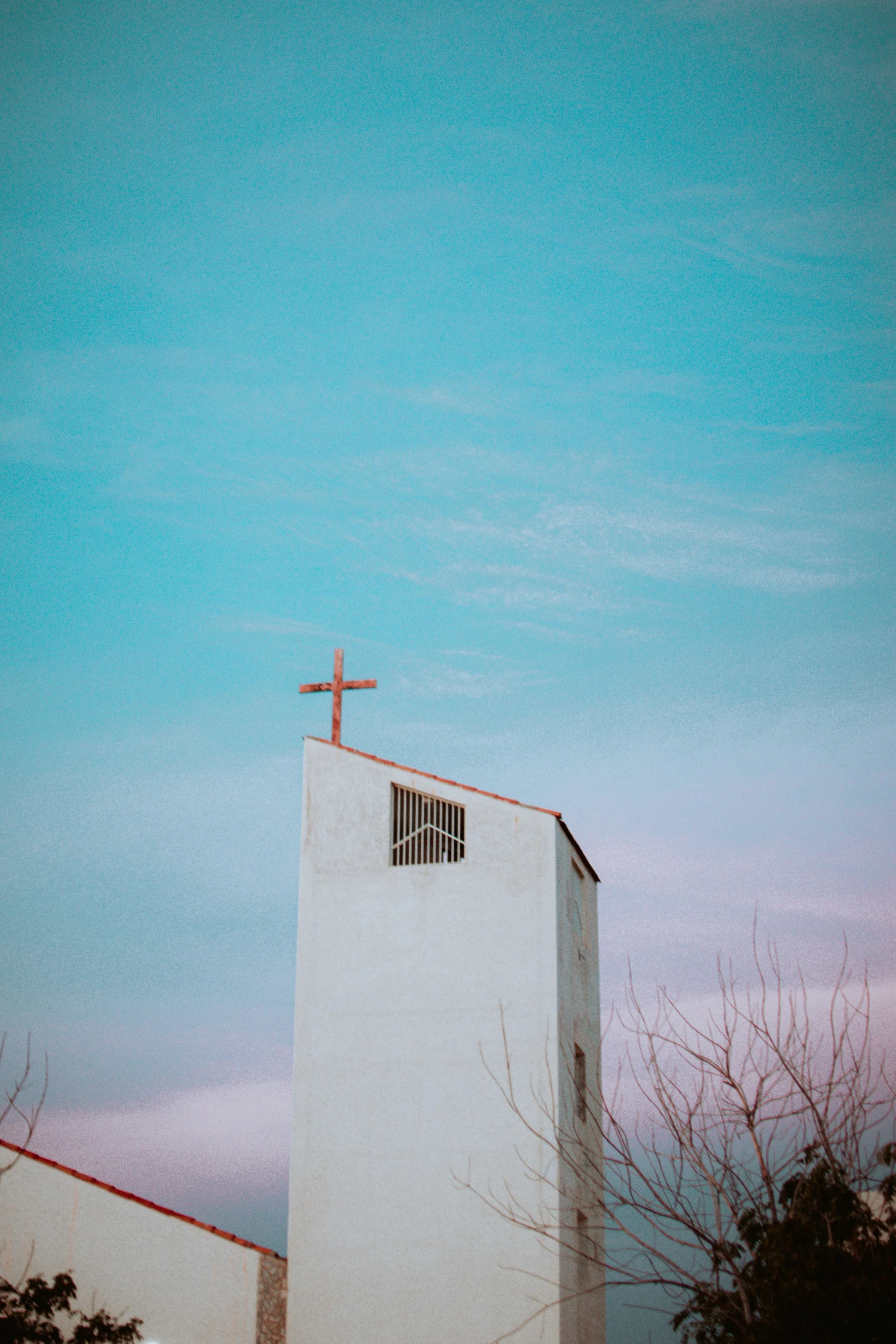 a church steeple against the dusk sky with cross on it