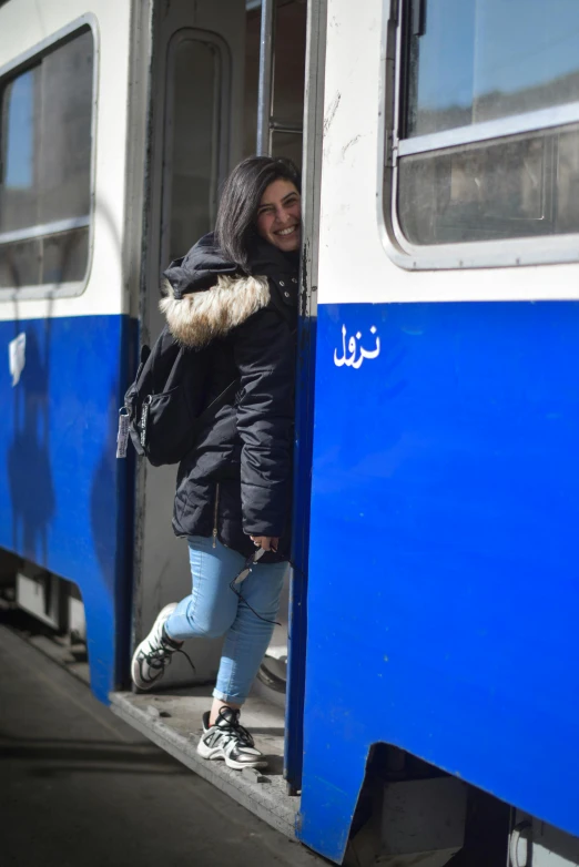 a girl leaning out the door of a commuter train