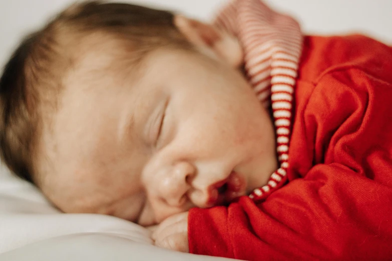 a small baby sleeps in a red jacket