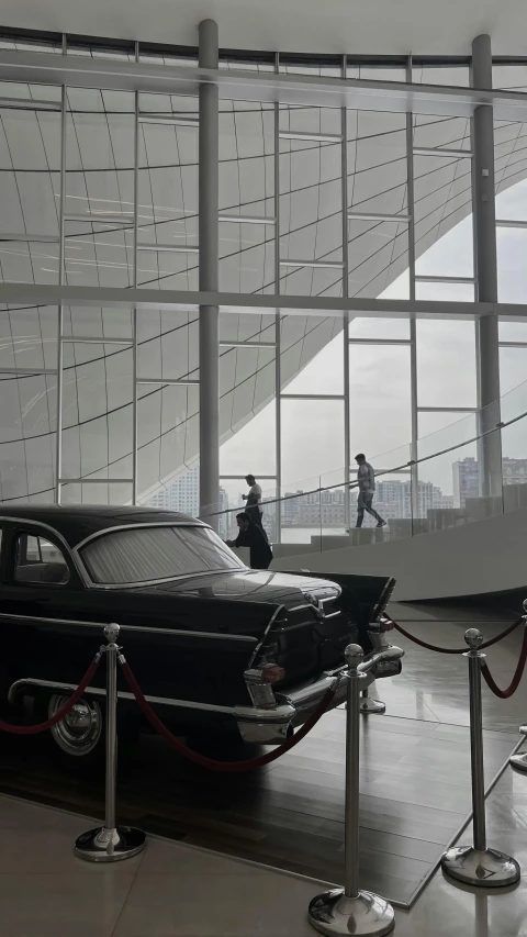 a classic car parked outside an artistic building with people looking out the window