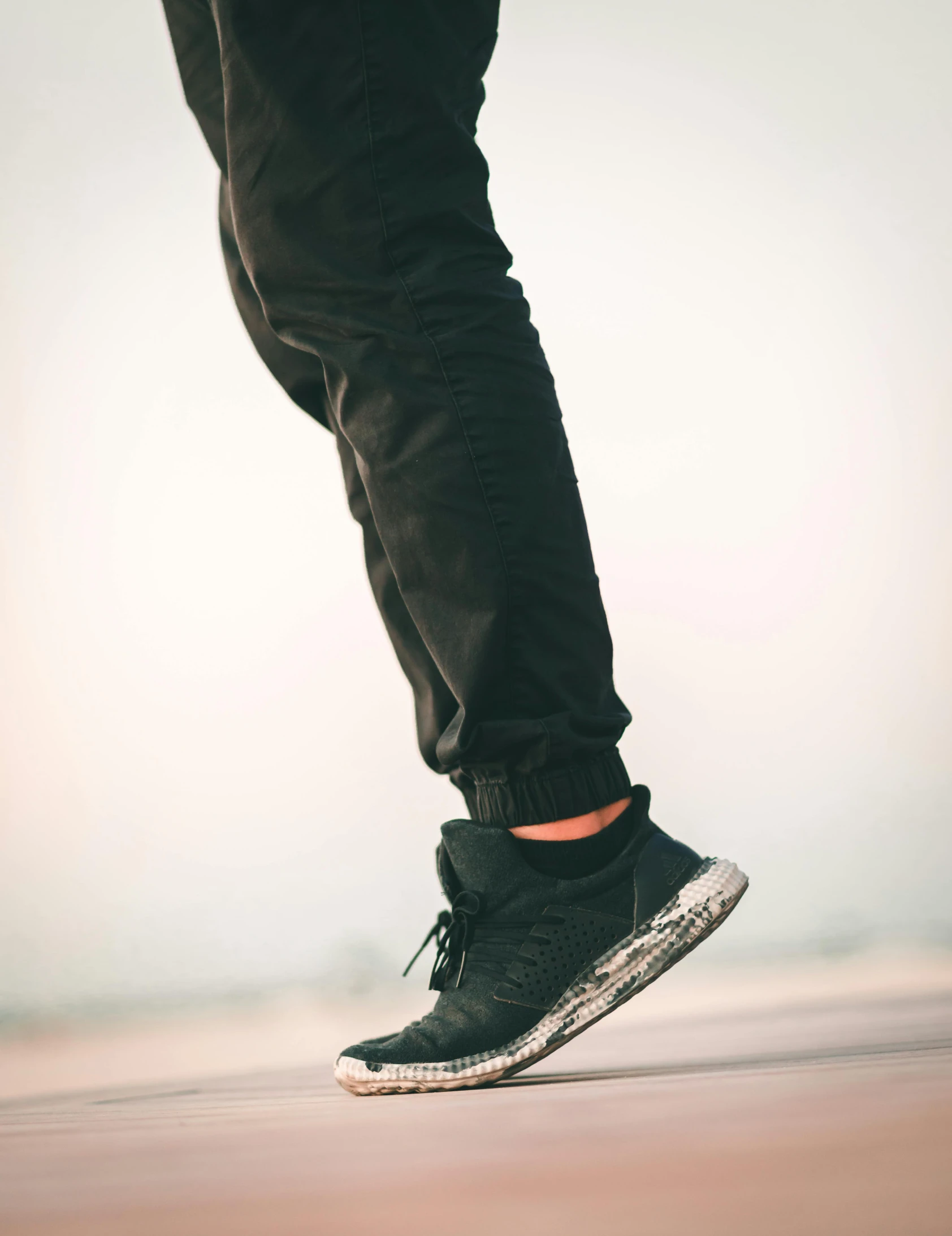 a person is wearing black shoes and stands on his skateboard