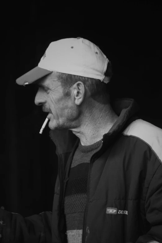 man in jacket smoking cigarette with hat on his head