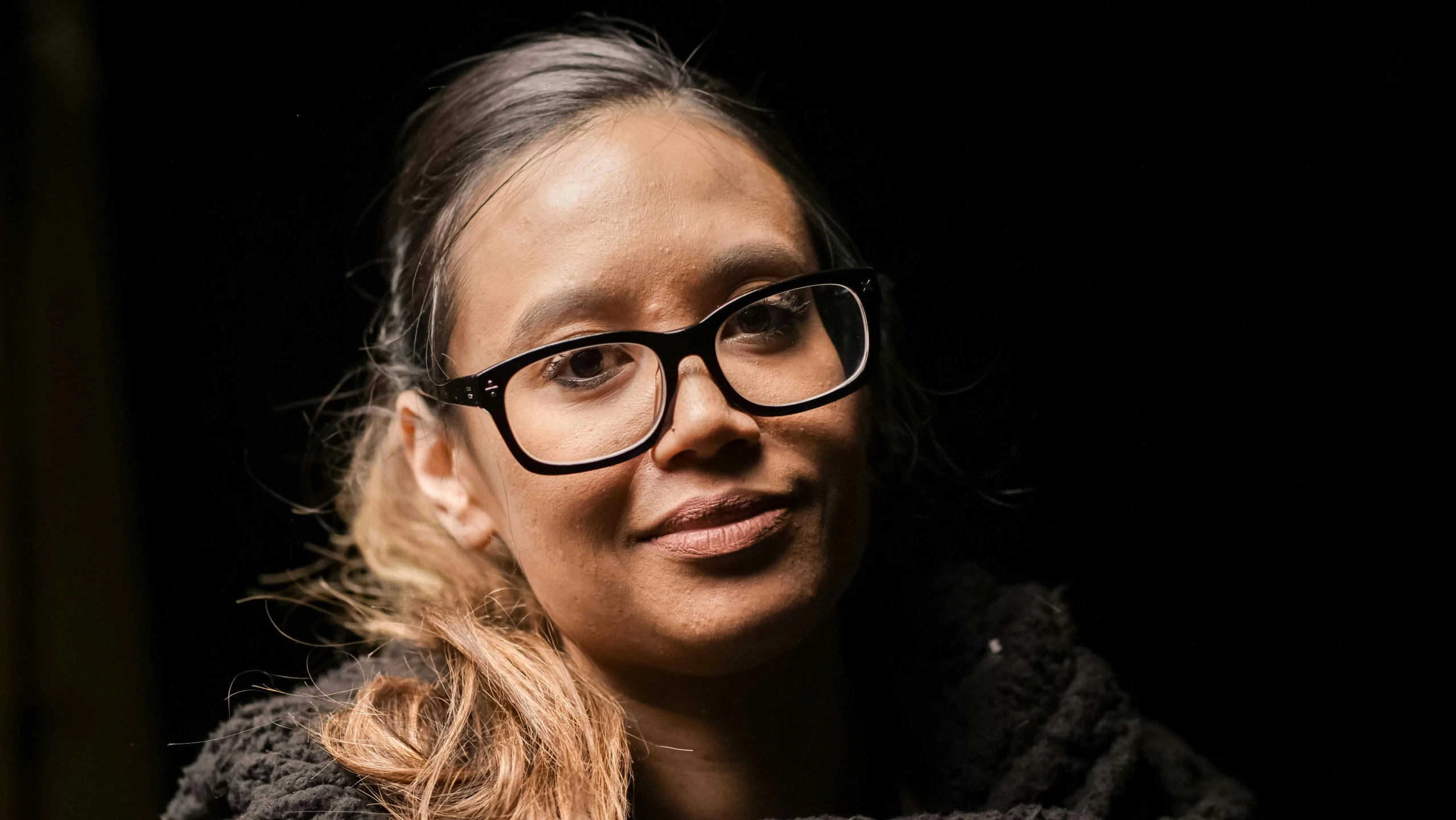 a woman with glasses and a brown blanket is looking off to the side