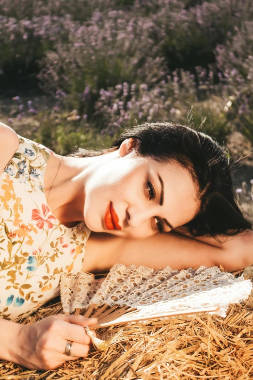 a beautiful young woman laying on hay with her arm around a book