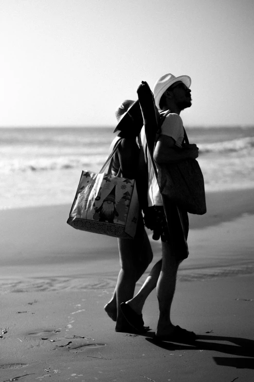 two women walk down the beach carrying bags