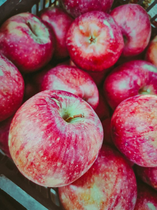 a crate full of red apples with one rotten