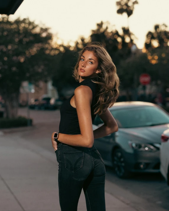 a woman standing in the street with a phone up to her neck