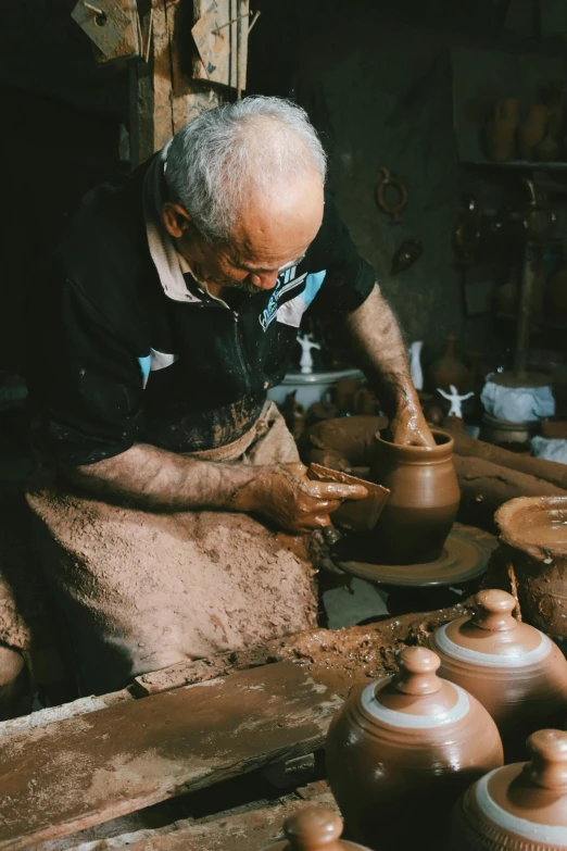 a man is making clay on an ancient potter's wheel