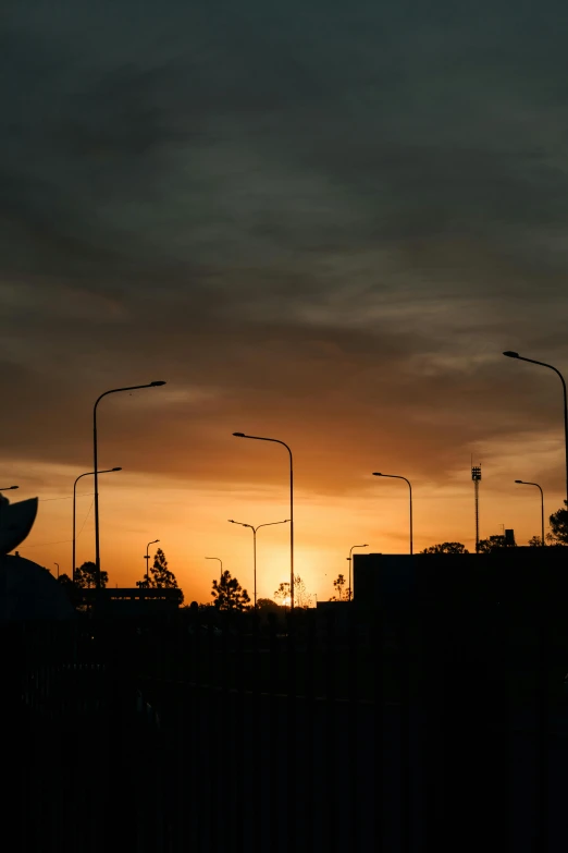 the sun is setting behind many street lamps