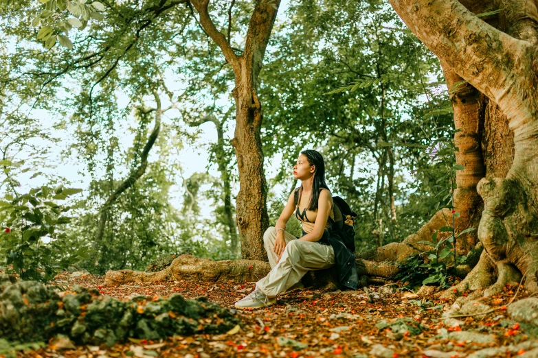 woman with head scarves sitting on tree nch surrounded by leaves