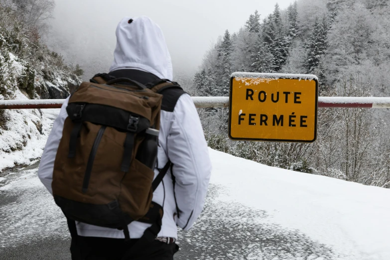 a man is looking at a sign on the road that warns of route fermee