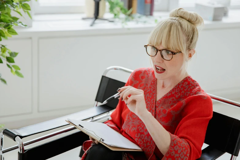 the woman is reading her paper while she is holding a pen