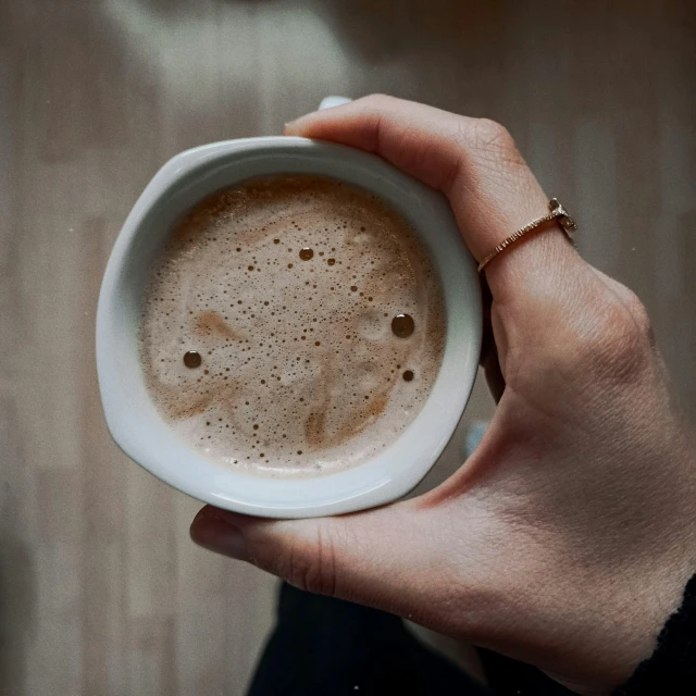 a hand holding a coffee cup with brown sprinkles