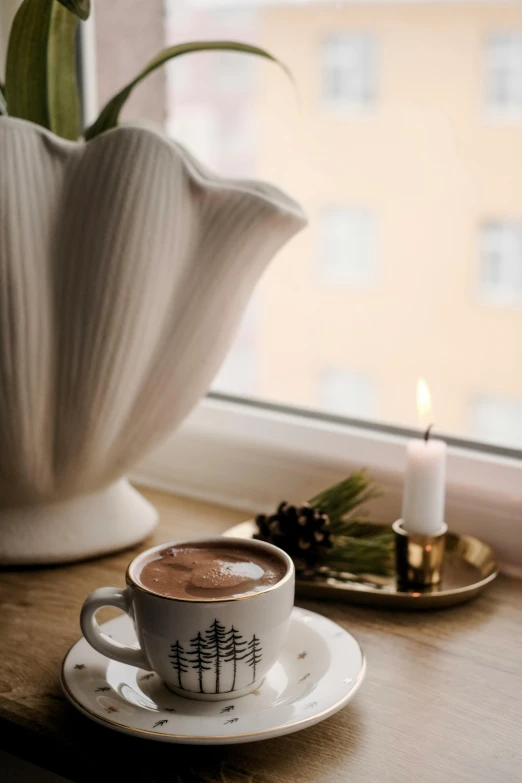 a cup of coffee with a small candle next to it