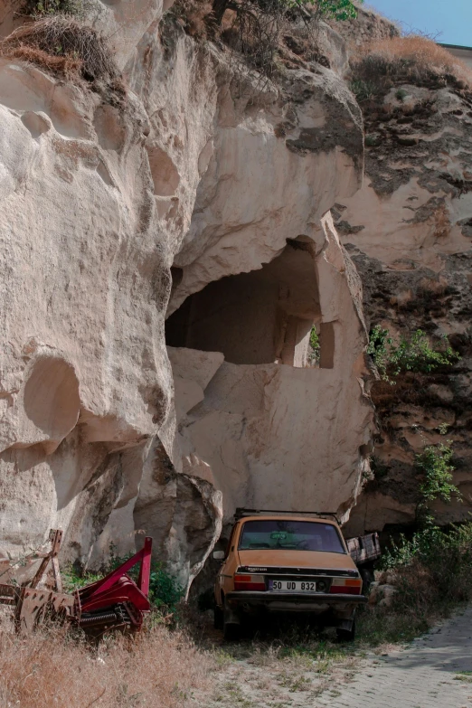 a small vehicle is in front of a massive rocky hill