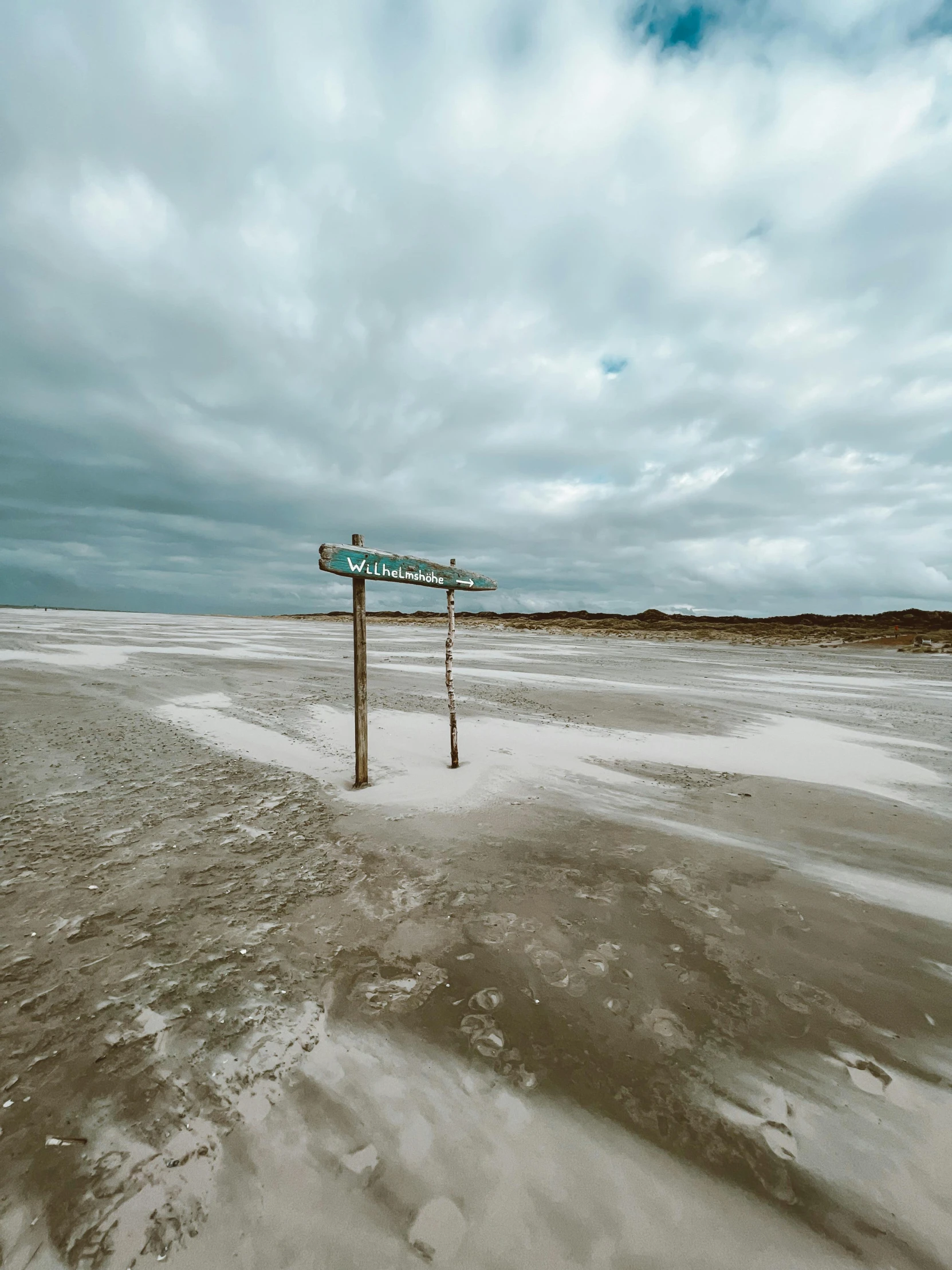 a beach with a sign in the foreground