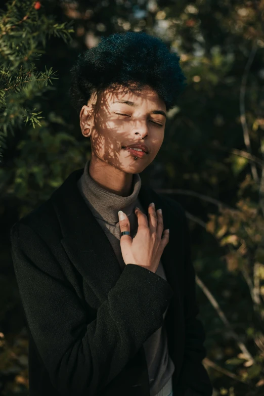 the young man is posing by a pine tree