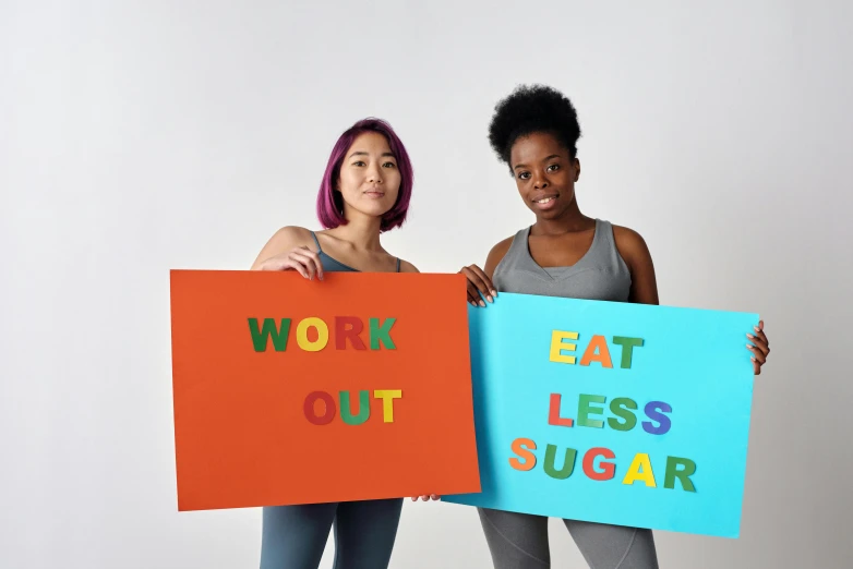 two women are holding up signs reading work, eat less sugar