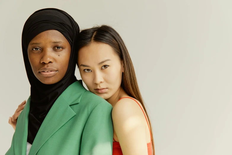 a young woman holding a younger one who is wearing a headscarf