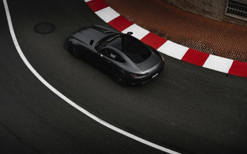 a black car driving down a street next to a red and white marker