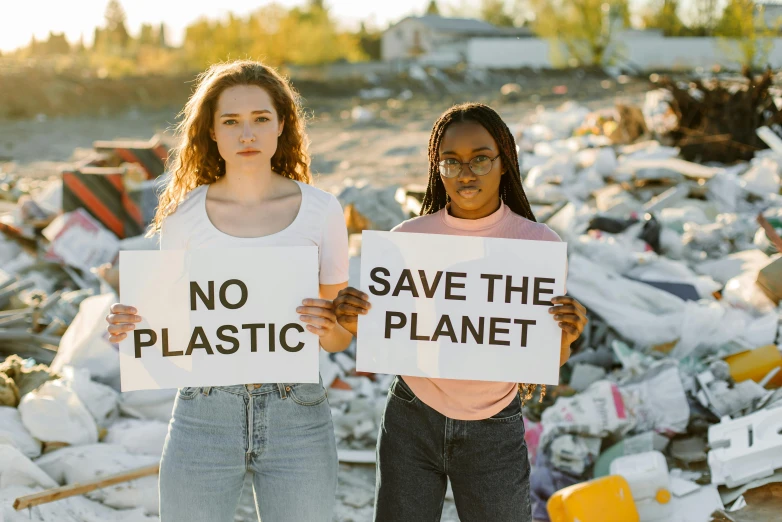 two girls holding signs that say no plastic, save the planet