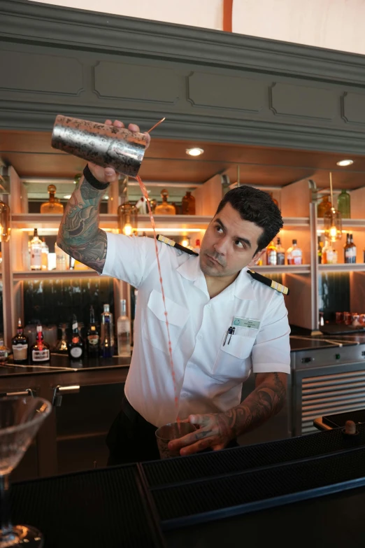 a man standing behind a bar pouring a drink