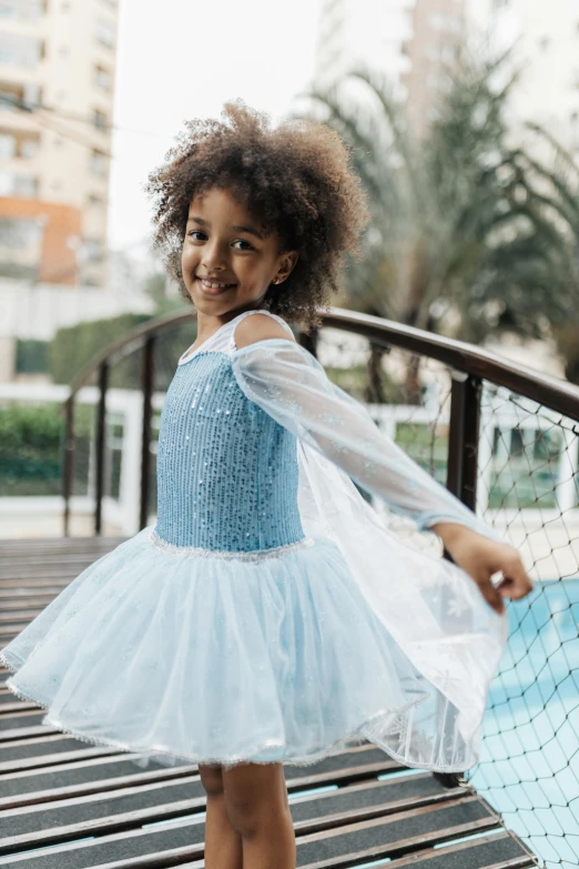 a little girl dressed in blue is holding an umbrella