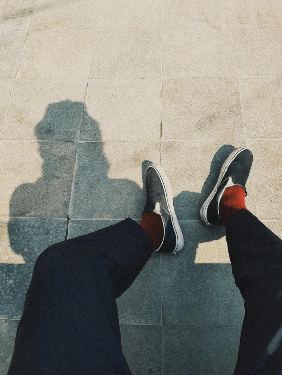 the shadow of someone wearing shoes on a floor