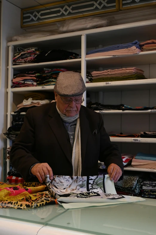 the old man wearing a hat is selecting clothing