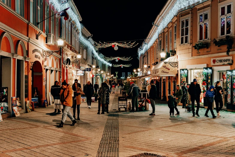 people walk in a narrow shopping center lit up with holiday lights