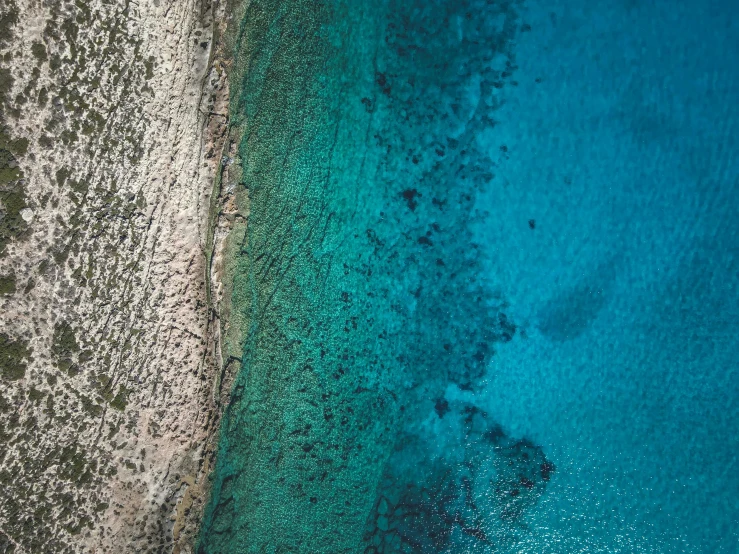 an aerial view of two waters and sand in a clear blue sea