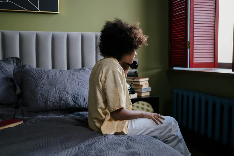 a girl wearing a yellow shirt sitting on a bed in her room