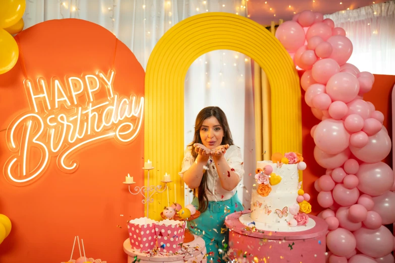 girl leaning on a birthday cake near a group of cakes