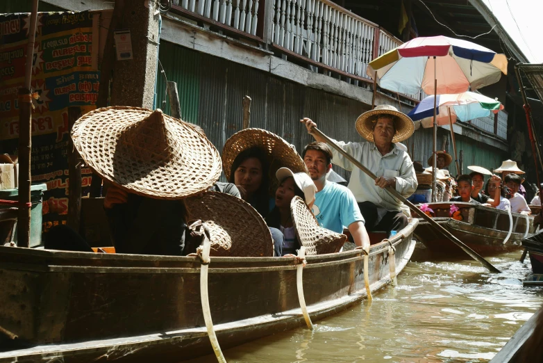 people sit in boats, while holding umbrellas and talking