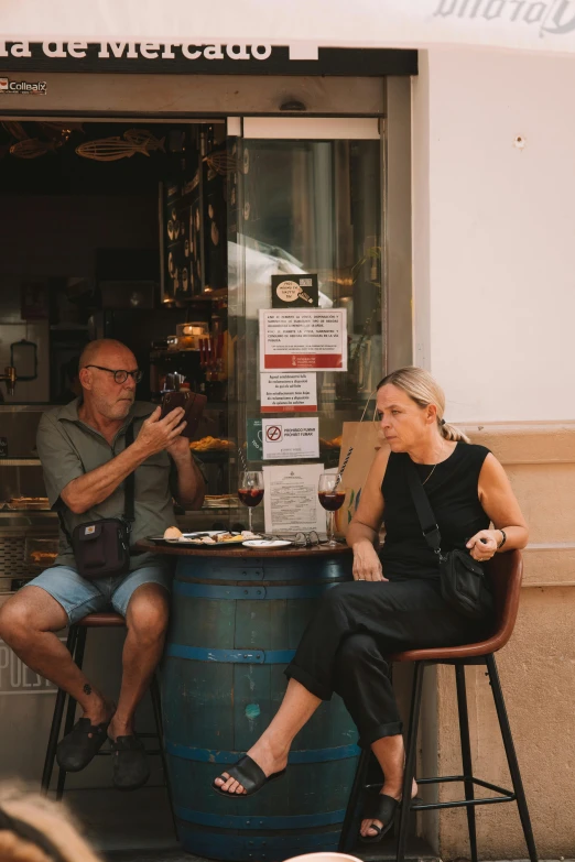 people sitting at a table outdoors with one of the women eating pizza