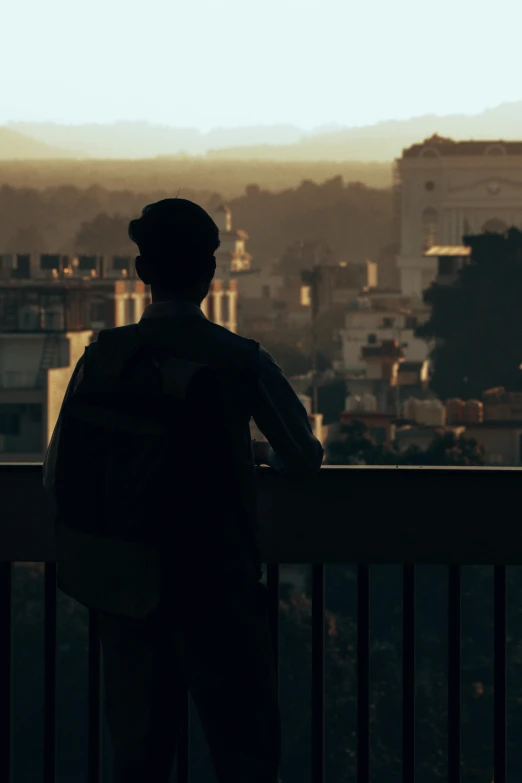 a man standing at a balcony looking out at the city