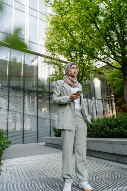 woman wearing a tan suit with a beige scarf stands in a public square