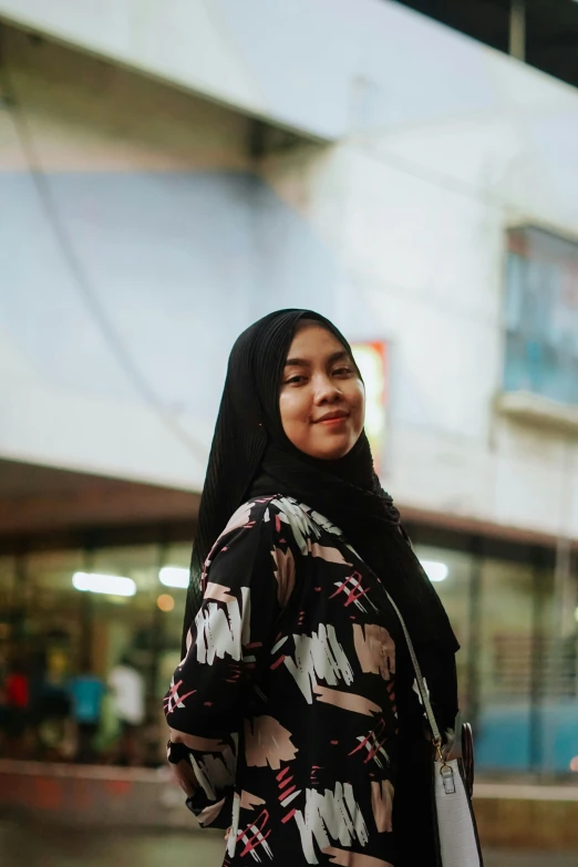 a girl is standing smiling while holding a shopping bag