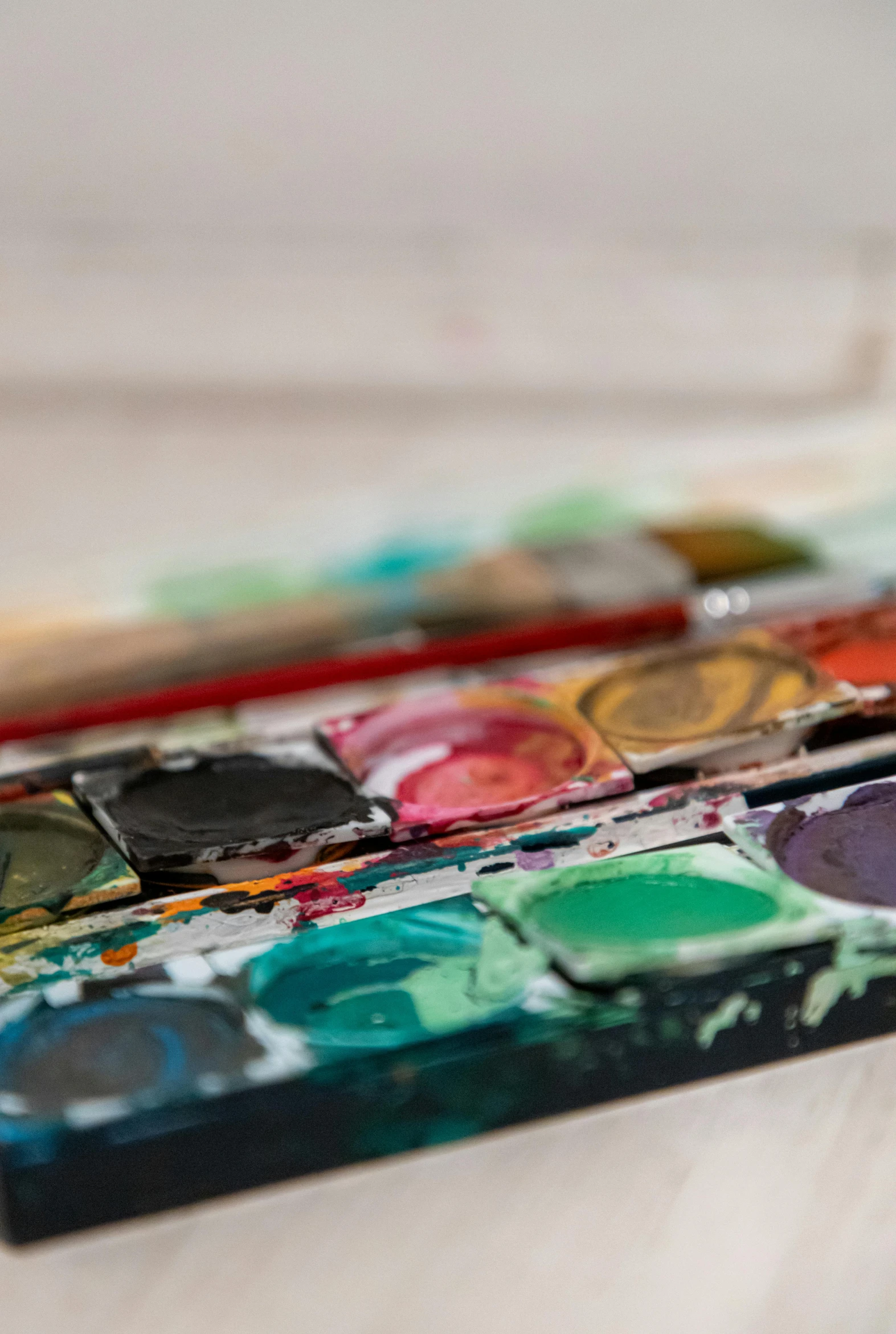 an empty paintbrush sitting on top of several watercolors