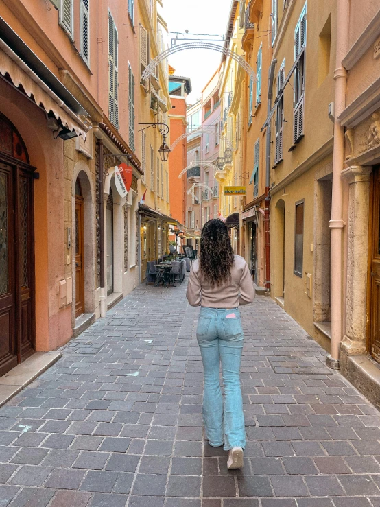 a woman is walking in a narrow alley way