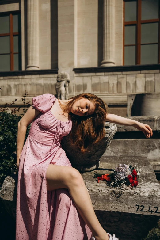 a woman in pink laying on stone steps near flowers