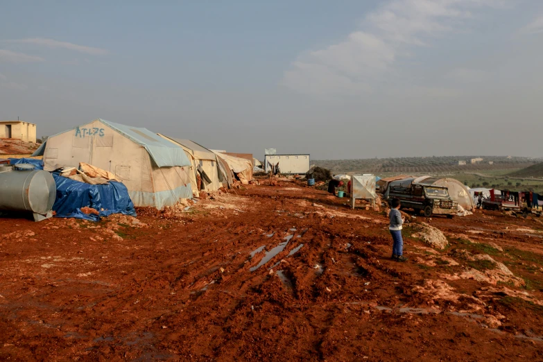 a person near several tents on a dirt surface