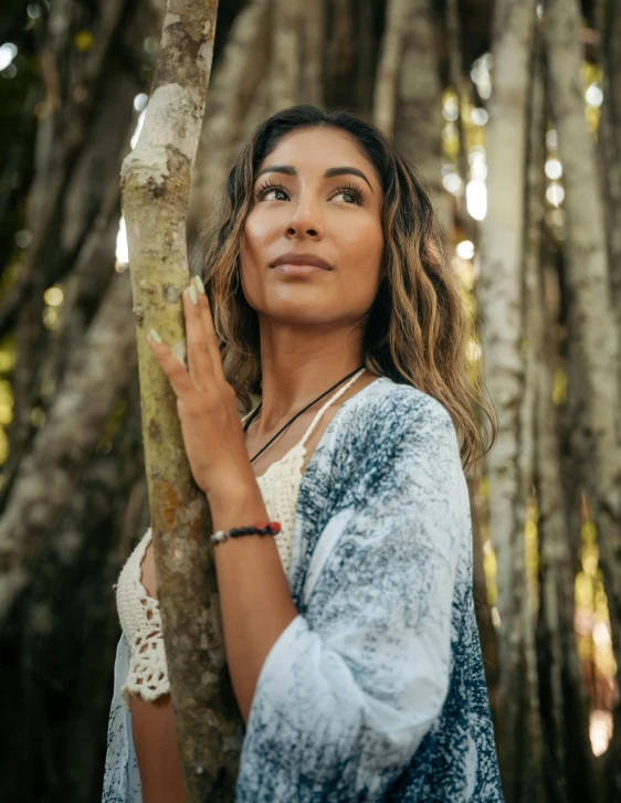 a woman standing behind a tree looking up