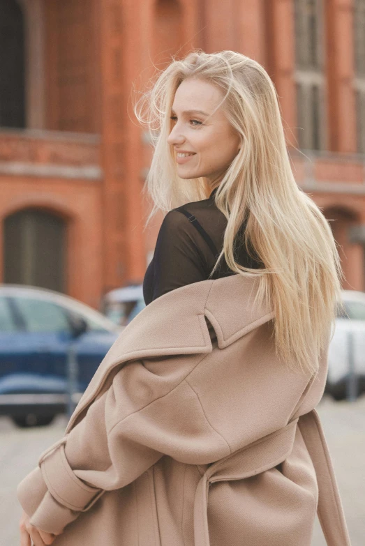 a woman with long blond hair is wearing a coat